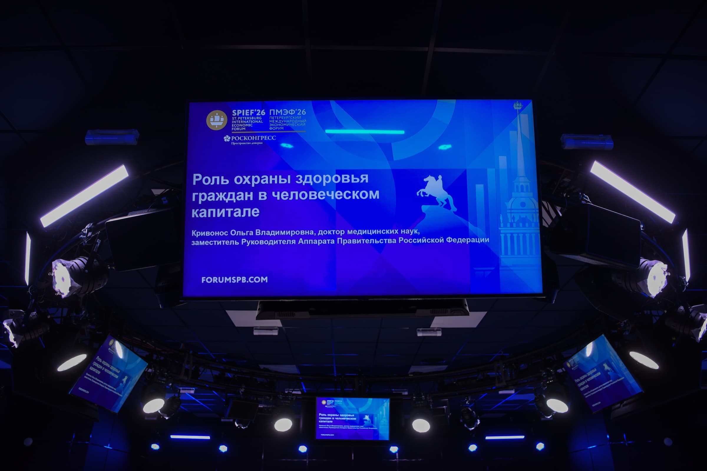 Pantalla suspendida en la sala de la sesión con la marca del SPIEF 2026 y el título de una presentación sobre el papel de la protección de la salud en el capital humano.