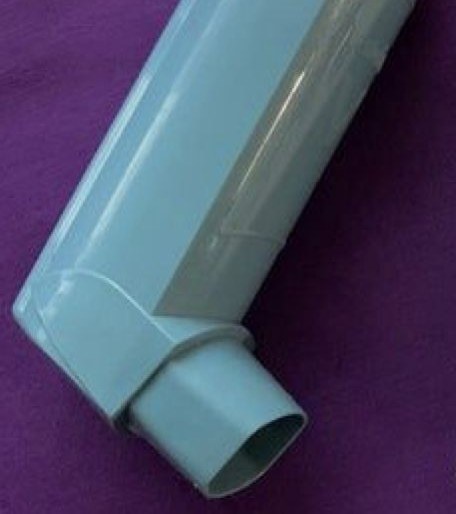 Inalador dosimetrado azul-claro em close sobre um fundo roxo