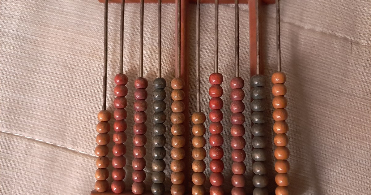 Ábaco de madeira com contas coloridas em fileiras sobre tecido bege