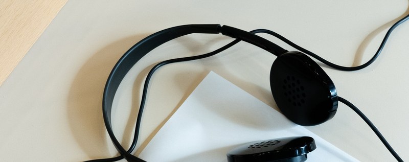 Fones de ouvido de interpretação simultânea sobre uma folha branca numa mesa clara