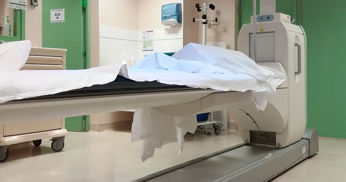 Mesa de exame de PET-CT coberta com lençol branco em sala de medicina nuclear