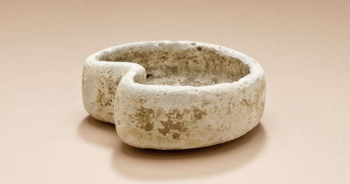 Antiga cuba em forma de rim feita de pedra clara sobre fundo bege liso