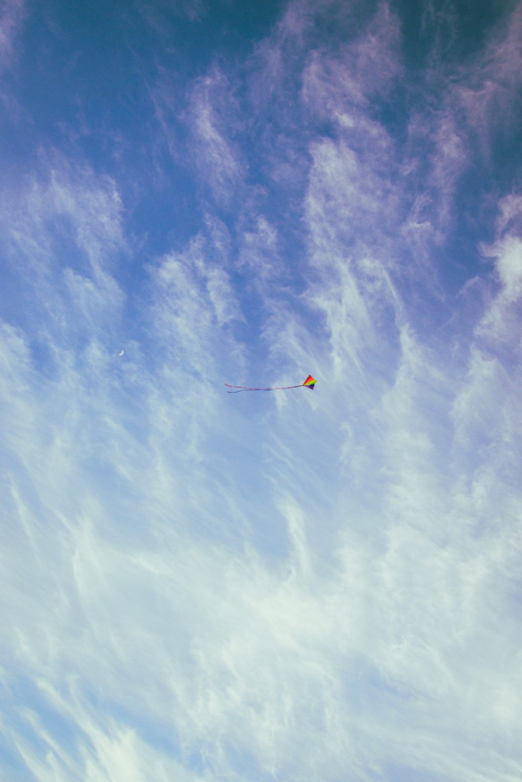 Cerf-volant coloré volant contre un ciel bleu avec des nuages blancs, vu d'en bas, à Oxwich.