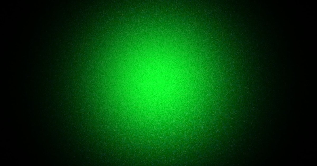 Mancha circular de luz verde de um feixe de laser projetada sobre fundo escuro
