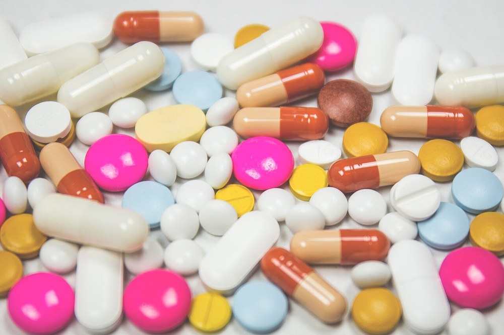 Cápsulas e comprimidos de várias cores espalhados sobre uma superfície