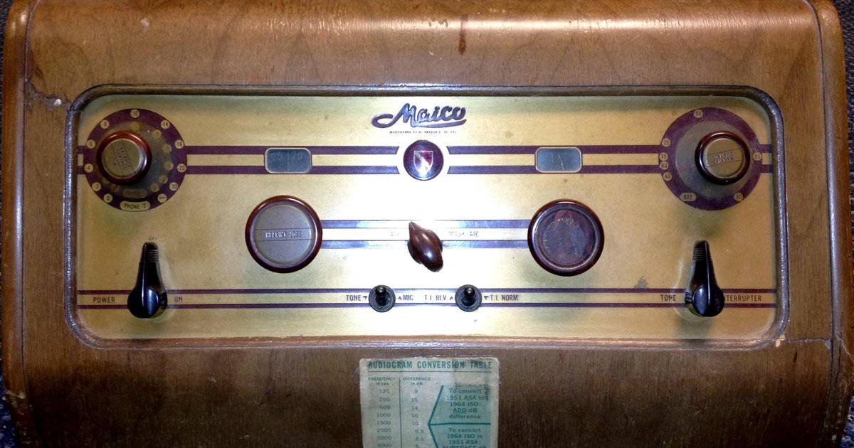 Audiômetro de mesa dos anos 1960 com diales e fones sobre superfície clara