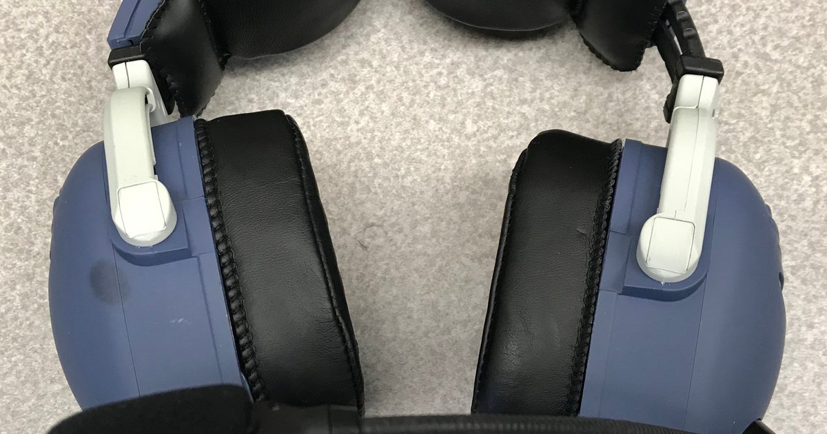 Fone de comunicação com conchas azuis e almofadas pretas apoiado sobre carpete cinza