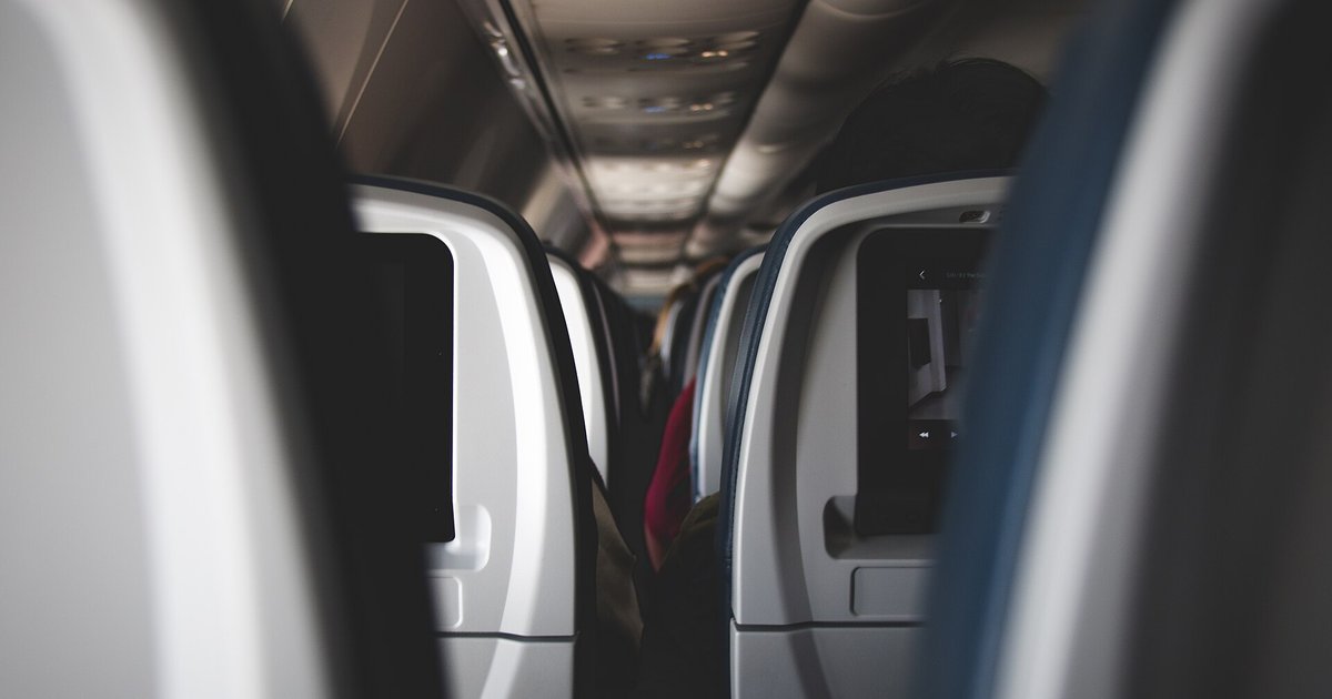 Fileiras de poltronas no corredor da cabine de um avião comercial
