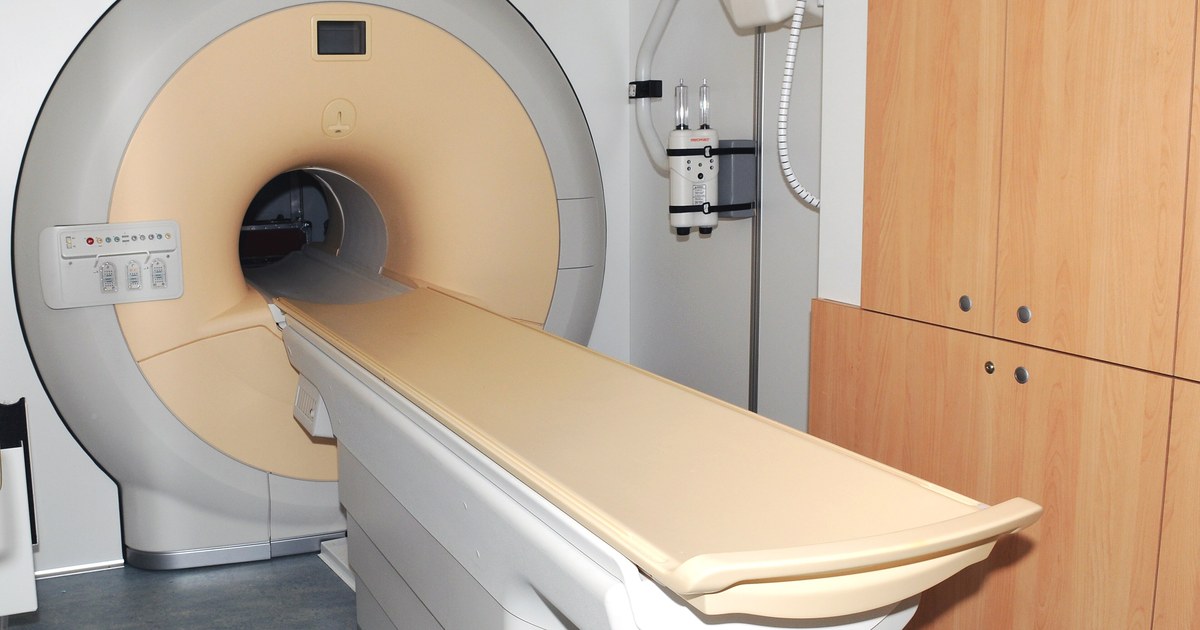 Aparelho de ressonância magnética com a mesa do paciente estendida em sala hospitalar