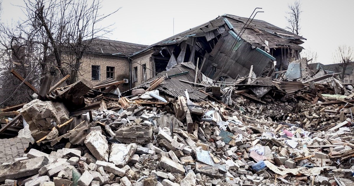 Escombros de um hospital destruído por bombardeio, com parte do prédio desabada ao fundo