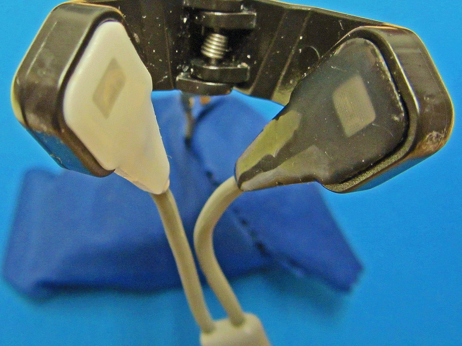 Sensor de oxímetro de pulso em forma de clipe, com duas almofadas de silicone e cabo claro, apoiado sobre um pano azul